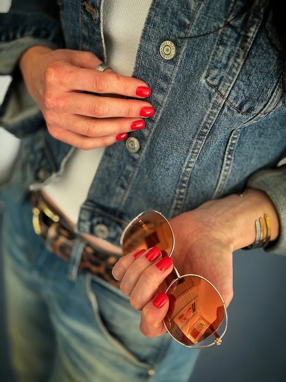 Rote Maniküre im Alltag mit Denim-Outfit und Sonnenbrille